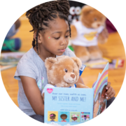 Build-A-Bear girl reading a book to a teddy bear